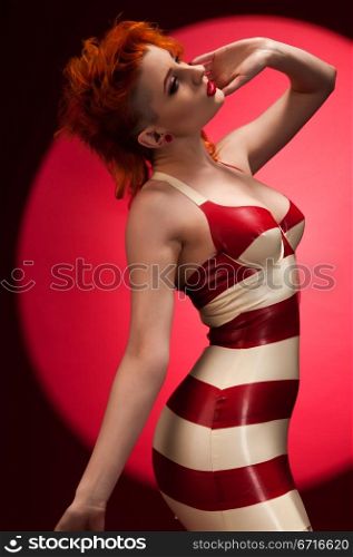 Pale slender redhead in latex fetish attire