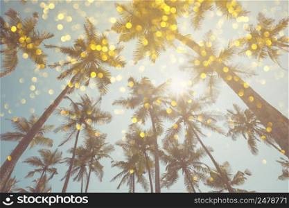 Palm trees vintage toned with shiny party bokeh glitter golden lights effect