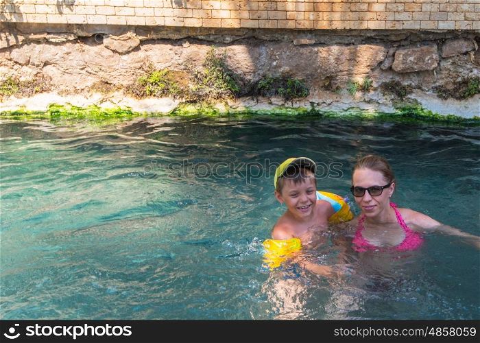 Pammukale, Turkey - July, 2015: photo of woman and her son at thermal Cleopatra pool in ancient city Hierapolis, near modern Turkey city Denizli