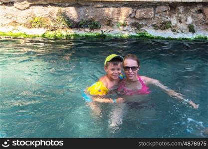 Pammukale, Turkey - July, 2015: photo of woman and her son at thermal Cleopatra pool in ancient city Hierapolis, near modern Turkey city Denizli