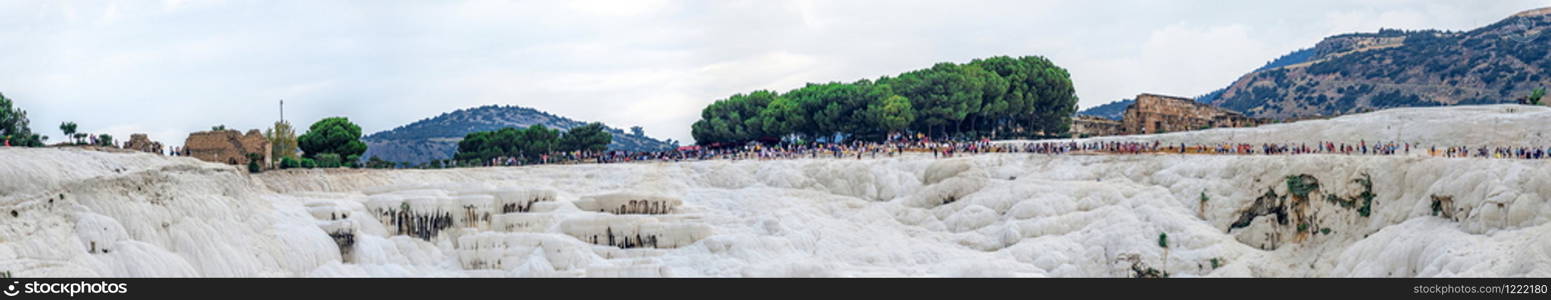 Pamukkale, Turkey ? 07.14.2019. Many tourists on Pamukkale white Mountain. Panoramic view from the side of the village on a cloudy summer evening.. Many tourists on Pamukkale Mountain in Turkey