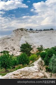 Pamukkale, Turkey ? 07.14.2019. Many tourists on Pamukkale white Mountain. Panoramic view from the side of the village on a cloudy summer evening.. Many tourists on Pamukkale Mountain in Turkey
