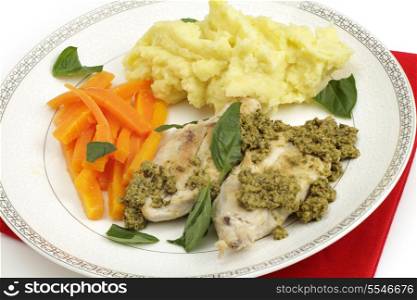 Pan fried chicken breasts served with pesto, julienned carrots, mashed potato and garnished with fresh basil leaves, a fusion of Italian and British cuisines. Shot with a tilt-shift lens for maximum depth of field.