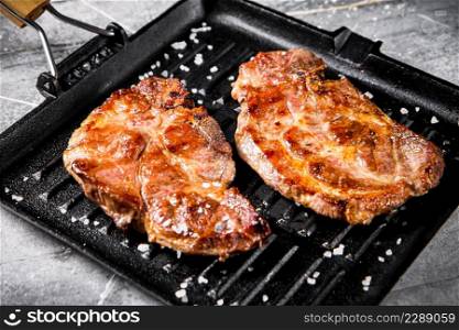 Pan fried grilled pork steak. On a gray background. High quality photo. Pan fried grilled pork steak.