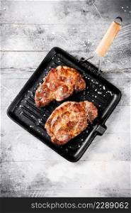 Pan fried grilled pork steak. On a gray background. High quality photo. Pan fried grilled pork steak.