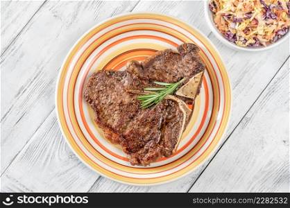 Pan-fried T-bone steak with fresh rosemary and pepper on the plate