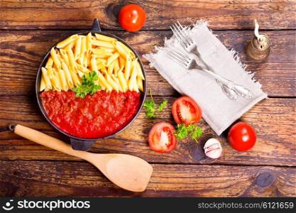 pan of pasta with tomato sauce on wooden table