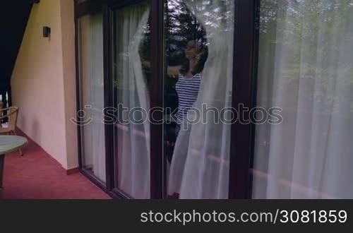 Pan of young woman coming on terrace to relax in the morning. Woman awakened from sleep breathing fresh air on villa balcony in summer. Slow motion