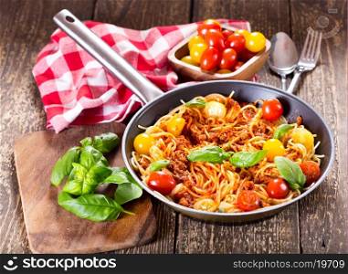 pan with spaghetti bolognese on wooden table