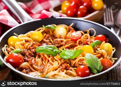 pan with spaghetti bolognese on wooden table