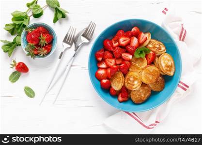Pancake cereal, mini pancakes with fresh strawberry in a bowl with maple syrup