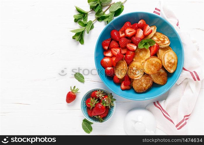 Pancake cereal, mini pancakes with fresh strawberry in a bowl with maple syrup