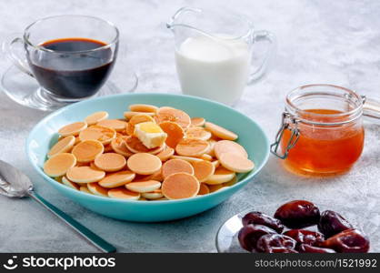 Pancake Cereal with Butter and Honey or Maple Syrup in Bowl on Grey Stone Table. Trendy Food Concept.. Pancake Cereal with Butter and Honey or Maple Syrup in Bowl on Grey Stone Table. Trendy Food Concept