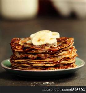 Pancake tower with fresh bananas and honey on a rustic table