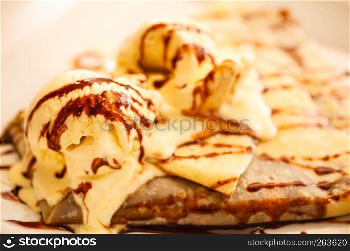 Pancake with ice cream and chocolate sauce on table