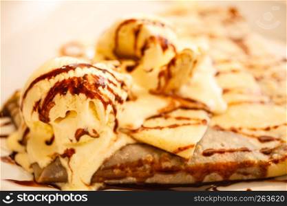 Pancake with ice cream and chocolate sauce on table