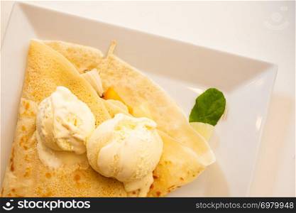 Pancake with ice cream on white plate top view