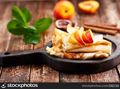 pancake with peach and cinnamon on the wooden board