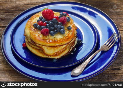 Pancakes . Pancakes with fresh berries on blue plate