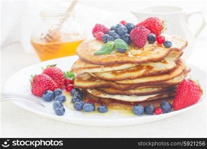 Pancakes . Pancakes with honey and fresh berries on white plate