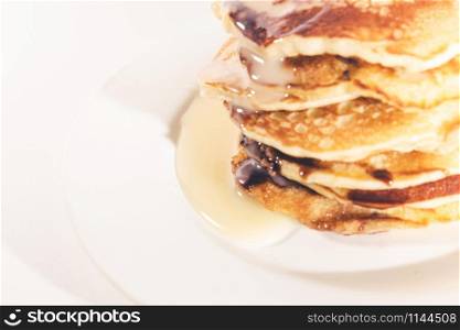 pancakes stacked on a white plate,Pancakes are topped with sweetened condensed milk.