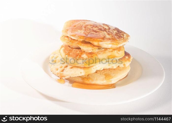 pancakes stacked on a white plate , The pancakes are topped with honey