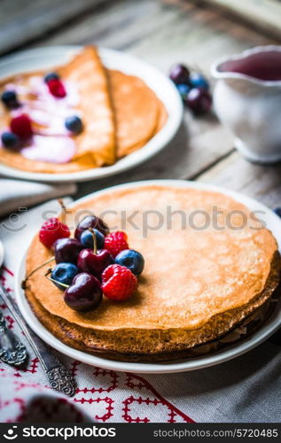 Pancakes with berries on wooden background