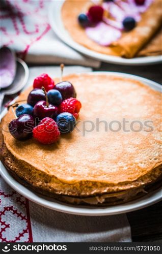 Pancakes with berries on wooden background