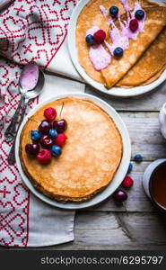 Pancakes with berries on wooden background