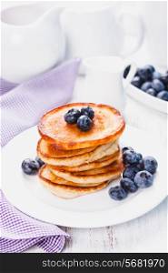 Pancakes with blueberry on a white plate and napkin
