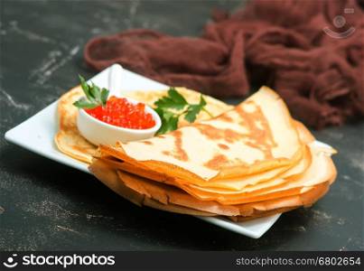 pancakes with caviar on the plate and on a table