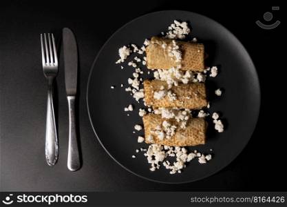 pancakes with cheese on a plate and kitchen utensils on a black background