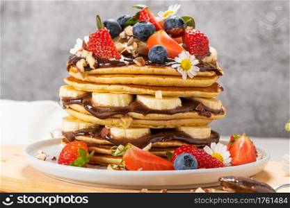 Pancakes with chocolate paste and hazelnuts, banana, strawberry and blueberry