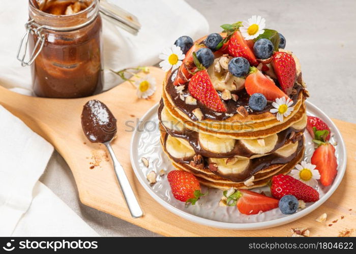 Pancakes with chocolate paste and hazelnuts, banana, strawberry and blueberry