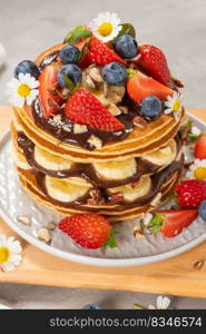 Pancakes with chocolate paste and hazelnuts, banana, strawberry and blueberry