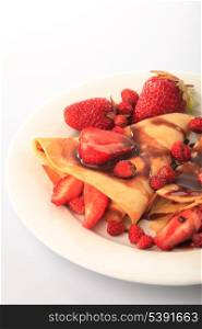Pancakes with different strawberries with chocolate syrup on white
