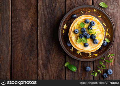 Pancakes with fresh blueberry on wooden rustic background. Top view
