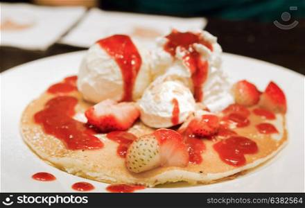 pancakes with ice cream , whipping cream , fresh strawberries and syrup .