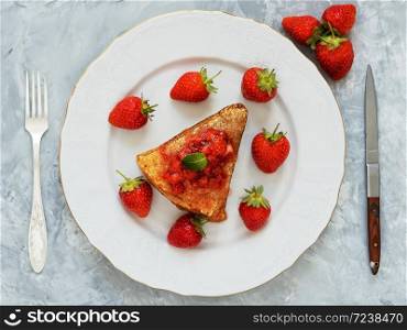 Pancakes with jam are located on a white plate, around the pancakes on a plate are fresh berries. Breakfast, festive food. Gray background Top view.