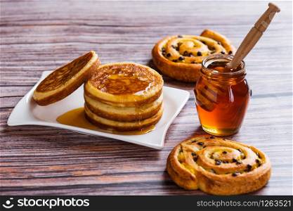 Pancakes with liquid honey on wooden background.