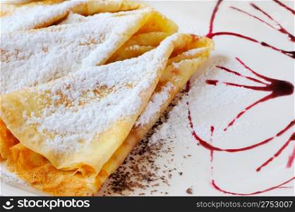 pancakes with powdered sugar. The dish is decorated by cowberry jam