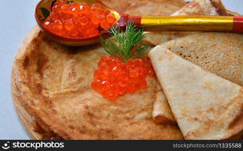 Pancakes with red caviar on the cutting board