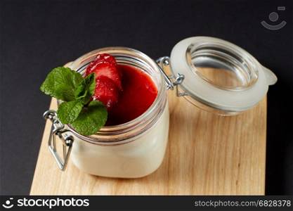 Panna cotta with mint in a glass jar on a rustic wooden table