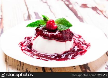 Panna cotta with raspberry sauce and mint leaf. The Panna cotta