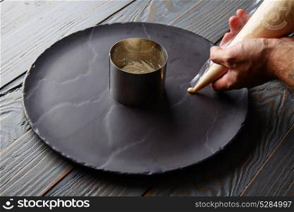 pannacotta preparation with chef hands on black slate dish