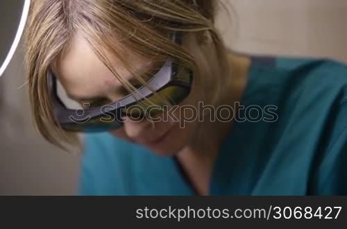 Panning down shot of doctor or therapist administering fractional skin laser treatment to resurface and rejuvenate a womans skin