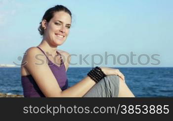 Panning on attractive young caucasian woman looking at the sea and smiling. Copy space