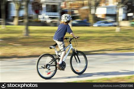 Panning shot of a boy riding a bicycle, motion blurred background