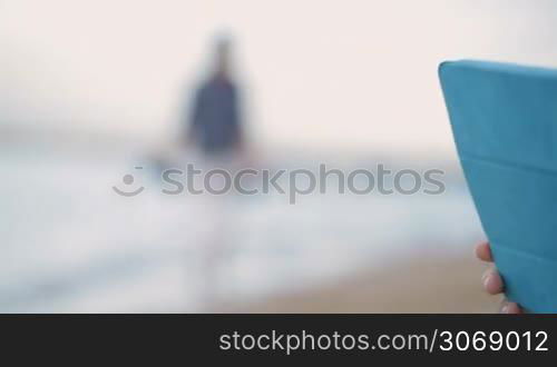 Panning shot of a lovely boy with his young mother using touchpad outdoor