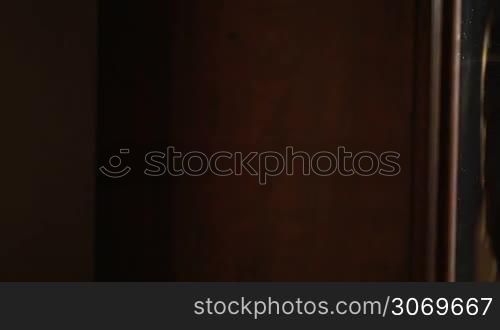 Panning shot of a young smiling woman taking a bottle of wine from cupboard
